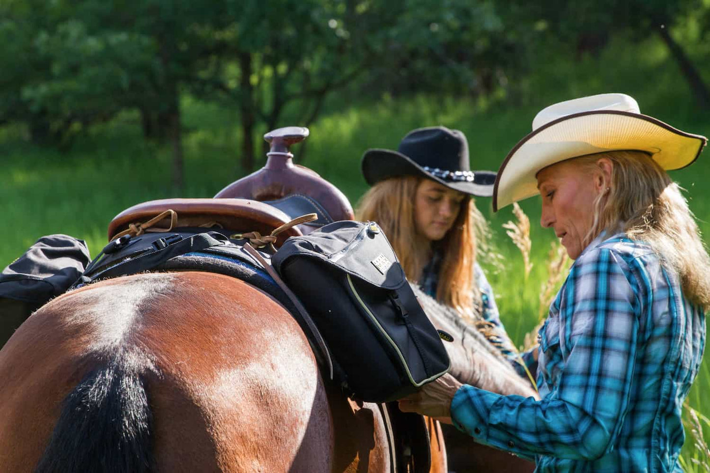 Two people preparing a horse for riding in a natural setting