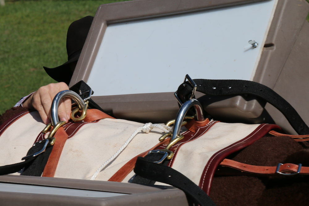 Closeup of a man attaching a hard-sided pannier to a Decker pack saddle using Decker hooks