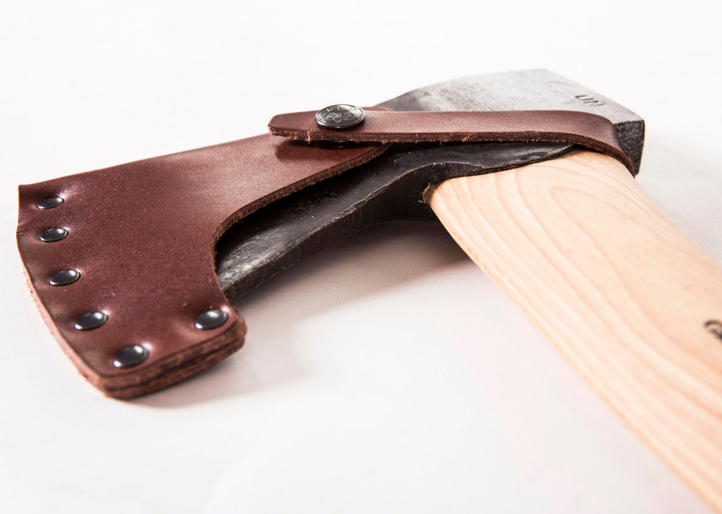 Close-up of a hatchet with a wooden handle and leather sheath on a white background