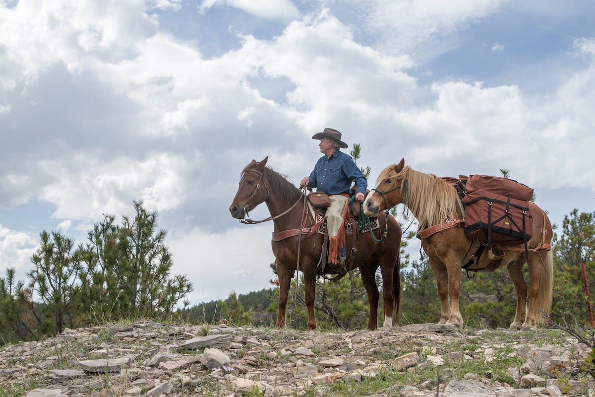 Man on horse with TrailMax saddlebags leading horse with TrailMax Pack-A-Saddle System on a pack saddle.