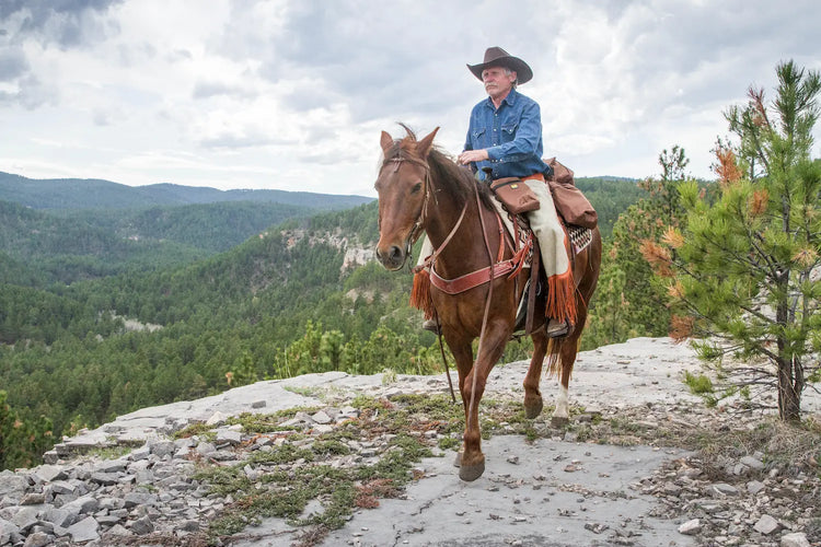 Man riding his horse with brown trailmax saddlebags on riding saddle