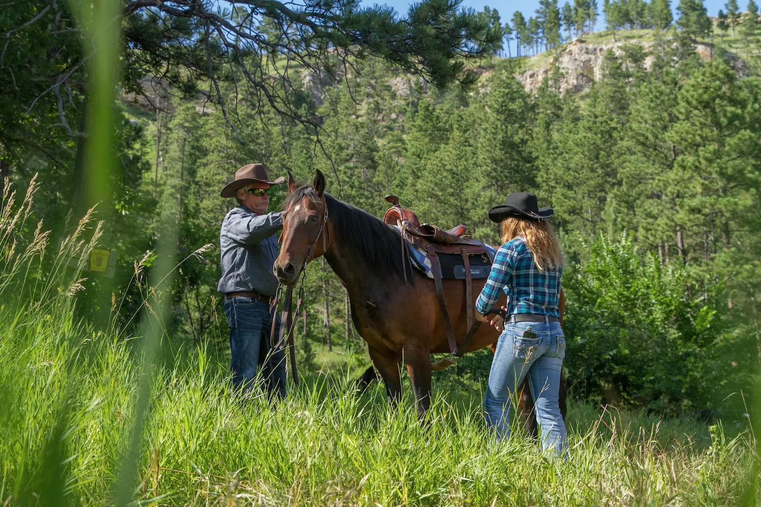 Girl tightening the cinch on a riding saddle on a horse
