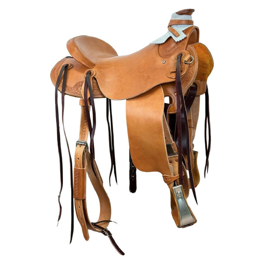 A classic light brown leather western saddle with tooled details, dark brown latigos and stainless steel hardware, isolated on a white background.